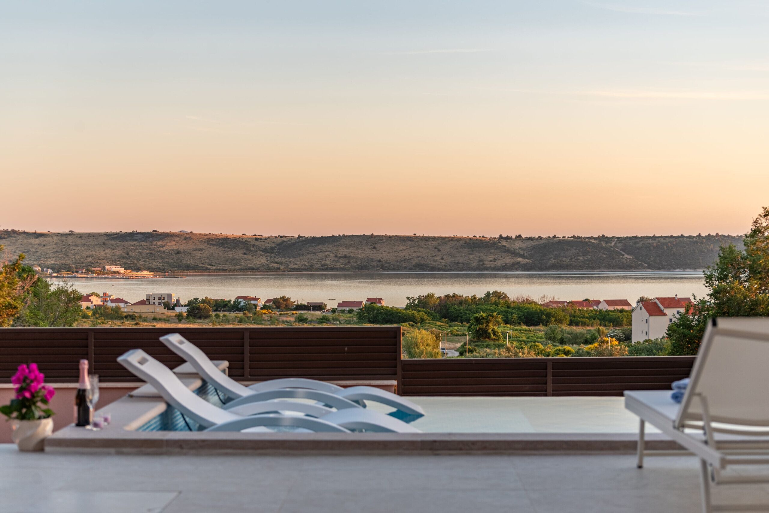 A rooftop terrace with lounge chairs and a view of a body of water.