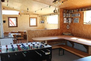 Ein gemütliches Zimmer mit einem Kicker, Holzwänden und Regalen mit Tassen.