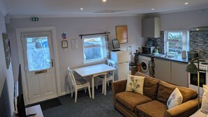 A compact living space with a kitchenette, a dining area, and a sofa. - The Highland Studio - Nc500's Home From Home (Muir of Ord)