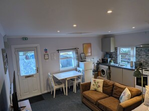 A compact living space with a kitchenette, a dining area, and a sofa. - The Highland Studio - Nc500's Home From Home (Muir of Ord)