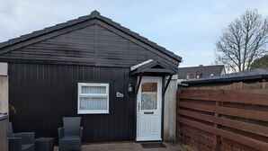 A black building with a white door, a small window, and a sign reading 'The Studio.' - The Highland Studio - Nc500's Home From Home (Muir of Ord)