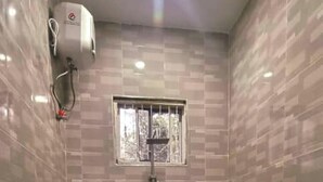 A small bathroom with a shower, toilet, and a window. - NAHITA APARTMENT (Zanzibar)