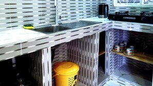 A kitchen with a modern design, featuring a stainless steel countertop, a sink, and a window with a view. - NAHITA APARTMENT (Zanzibar)