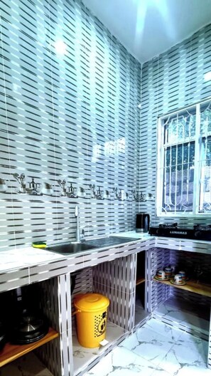 A kitchen with a modern design, featuring a stainless steel countertop, a sink, and a window with a view. - NAHITA APARTMENT (Zanzibar)