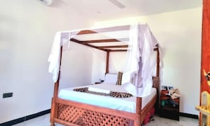 A four-poster bed with a canopy, a bedside table, and a nightstand. - NAHITA APARTMENT (Zanzibar)