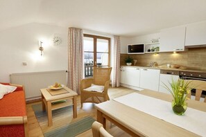Un espacio habitable compacto con kitchenette, comedor, sofá y ventana con cortinas.