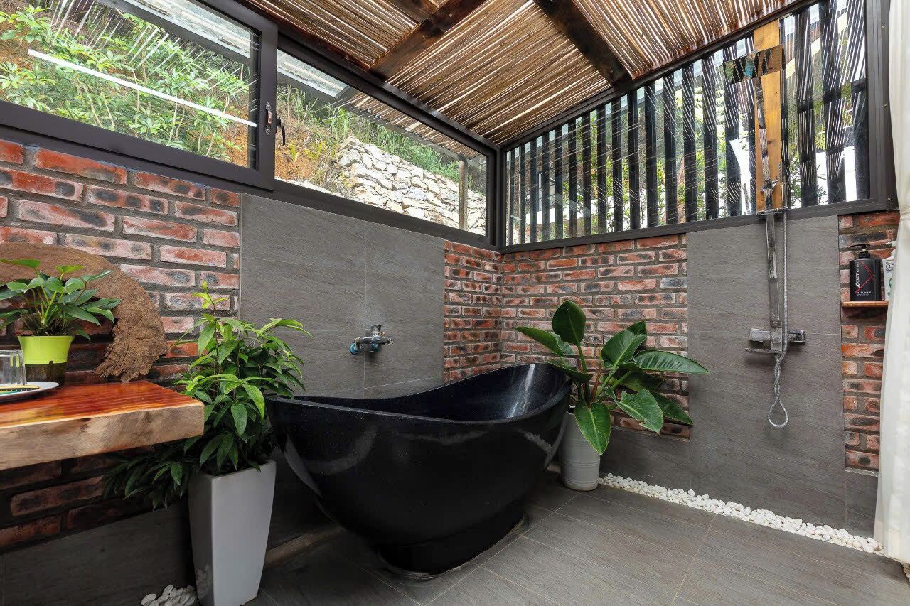 A modern bathroom with a black freestanding bathtub, a wooden countertop, and potted plants.