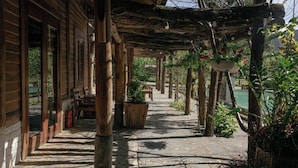 A covered outdoor area with wooden pillars, potted plants, and a stone pathway. - The Nordic Village Moc Chau (Van Ho)