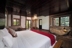 Ein Schlafzimmer mit einem großen Bett, einem Becken aus Stein und Blick ins Freie.