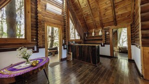 A log cabin interior with a wooden ceiling, a central table with a vase, and a bench. - The Nordic Village Moc Chau (Van Ho)