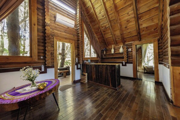 Ein rustikales Holzhaus-Interieur mit Holzbalkendecke, einem Tisch in der Mitte und einer Bank.