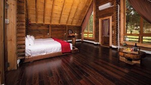 A log cabin bedroom with a bed, wooden walls, a wooden ceiling, and large windows. - The Nordic Village Moc Chau (Van Ho)