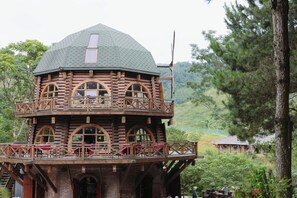 Une cabane en rondins dotĂ©e dâun balcon et de fenĂȘtres en arc de cercle.