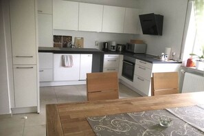Eine moderne Küche mit weißen Schränken, einem Holztisch und einer Mikrowelle.