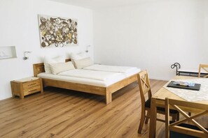 Ein Schlafzimmer mit einem hölzernen Bett, einem kleinen Nachttisch, einem Stuhl und einem Tisch mit einem Buch.