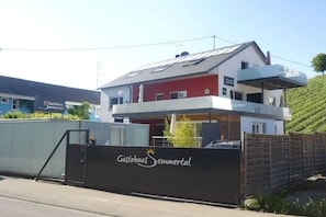 Ein zweistöckiges Gebäude mit roter und weißer Fassade, einem verschlossenen Eingang und einem Schild mit der Aufschrift 'Gästehaus Sommerental'.