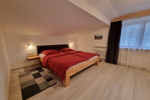 Ein Schlafzimmer mit Bett, Nachttischen, einem Heizkörper, einem Fenster mit Vorhängen und einem Teppich.