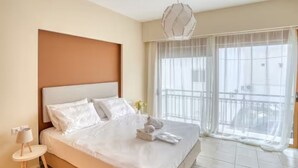 A hotel room with a large bed, a bedside table, a hanging light fixture, and a balcony with a view. - Azure Seaside Living Kardamaina-10m from the sea (Kardamaina)