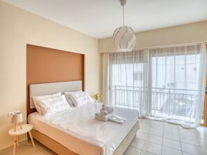 Ein Hotelzimmer mit einem großen Bett, einem Nachttisch, einer Hängelampe und einem Balkon mit Blick.