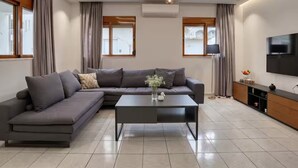 A modern living room with a sectional sofa, a coffee table, a TV, and a flat-screen TV mounted on the wall. - Azure Seaside Living Kardamaina-10m from the sea (Kardamaina)