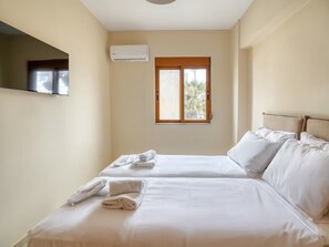 Ein Hotelzimmer mit zwei Betten, einem Fenster mit Aussicht, einer Klimaanlage und einem flachbildfernseher, der an der Wand angebracht ist.