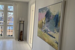 Ein Zimmer mit einem großen, abstrakten Gemälde, einer Stehlampe und Blick durch eine Glastür.