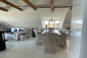 Ein Loft-Zimmer mit Essbereich, weißen Möbeln und einem Fenster mit Blick.