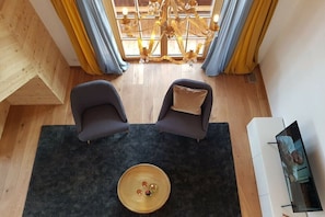 Ein Zimmer mit zwei Sofas, einem Couchtisch, einem Fernseher und einer Kristallleuchter.