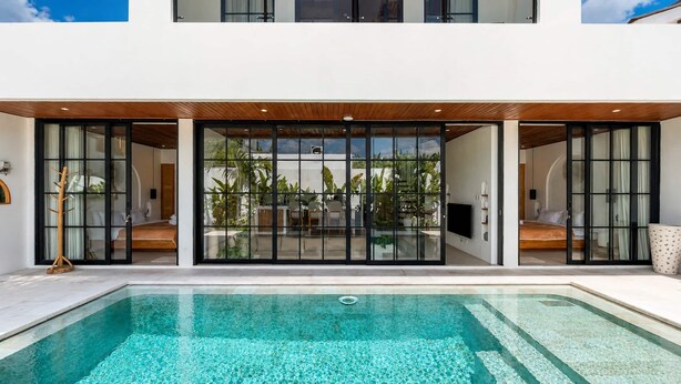 Uma casa moderna com piscina, grandes portas de vidro e vista para o jardim.