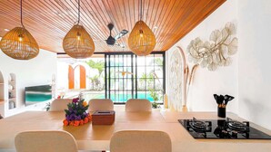 Uma área de refeições com vista para a piscina, teto de madeira e decoração moderna.