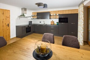 Eine moderne Küche mit dunklen Schränken, einem Holztisch und einem Kerzenpräsentationsstück aus Glas.