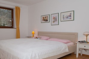 A bedroom with a bed, a nightstand, a lamp, and three framed pictures on the wall. - in the house on Hachelbach (Schliersee)