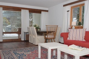 A living room with a red sofa, a white coffee table, a wooden chair, and a dining table with chairs. - in the house on Hachelbach (Schliersee)