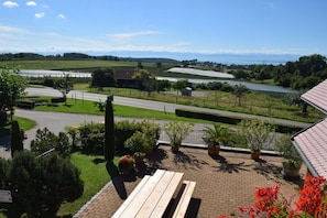 A view of a rural landscape with a road, fields, and a body of water. - Geiger - Säntisblick (Meersburg)