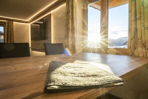 A wooden table with a textured placemat, a chair, and a window with curtains. - Holiday apartment with 3 bedrooms (Oberstdorf-Schöllang)
