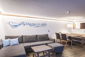 Ein modernes Wohnzimmer mit einem grauen Sofa, einem Holztisch und einem Essbereich mit Stühlen und einem Tisch.