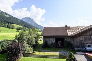 Une grange en bois, dotée d’un toit à pente, entourée d’une pelouse bien entretenue et d’une zone délimitée par une clôture.