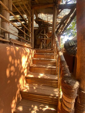 Una escalera de madera con barandilla que conduce a una zona cubierta con techo.