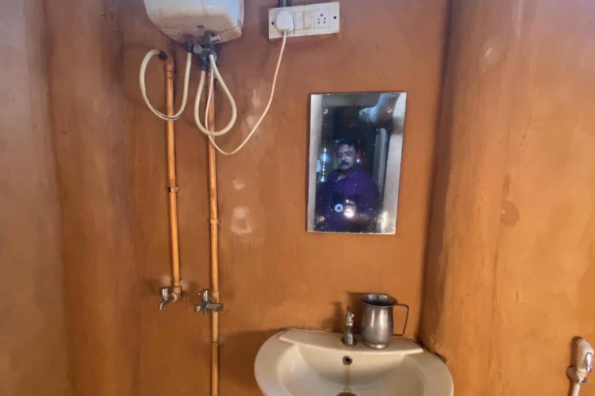 Ein Badezimmer mit Waschbecken, Spiegel, Duschbrause und Eimer.