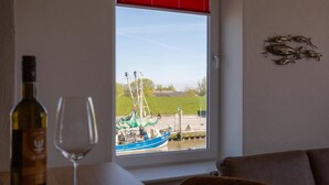 Une pièce avec vue sur un quai, une bouteille de vin et un verre sur une table.
