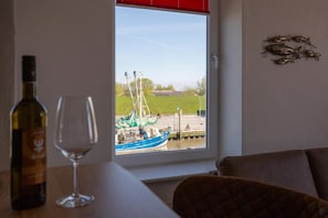 Ett rum med utsikt över en brygga, en vinflaska och ett glas på ett bord.