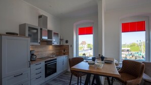 Une cuisine moderne avec des meubles blancs, un plan de travail en bois et un coin repas comprenant une table et des chaises.