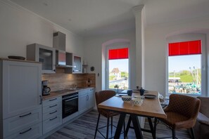 Cozinha moderna com armários brancos, bancada de madeira e área de jantar com mesa e cadeiras.