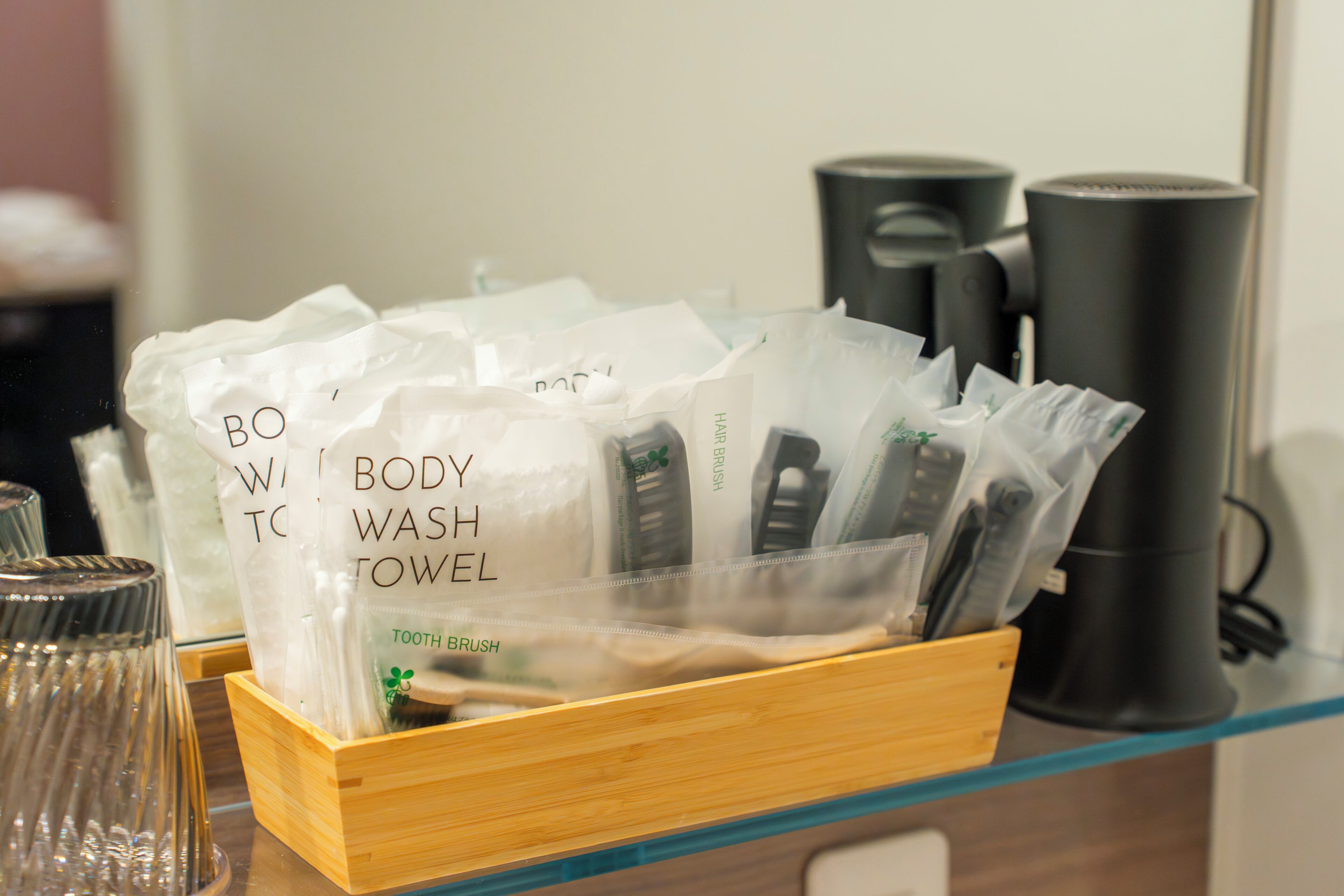 A wooden tray holding white towels labeled 'BODY WASH TOWEL' and a toothbrush.