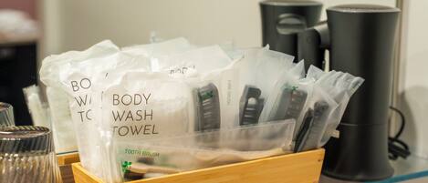A wooden tray holding white towels labeled 'BODY WASH TOWEL' and a toothbrush.