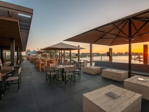 An outdoor seating area with tables and chairs, umbrellas, and a view of the water. - Family Villa With Ambient Fireplace (Tholen)