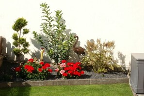 Ein Garten mit verschiedenen Pflanzen und einer Vogelstatur.