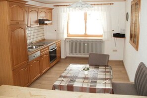 Une cuisine compacte avec des meubles en bois, un four encastré et un coin repas comprenant une table et des chaises.