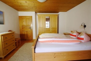 Ein Schlafzimmer mit einem hölzernen Bett, einer Holzkommode und einer Tür zu einem anderen Raum.