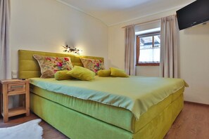 Ein Schlafzimmer mit einem Bett, einem Nachttisch, einem Fernseher und einem Fenster mit Vorhängen.